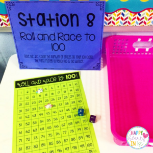 Students play a math center game to celebrate the 100th day of school in first grade stations